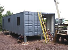 two men are working on the side of a shipping container that's being built