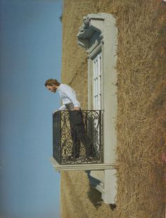 a man standing on top of a balcony next to a building