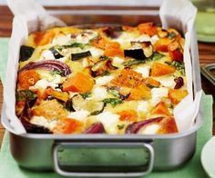 a casserole dish with vegetables in it on a green place mat next to silver utensils