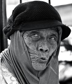 an old woman wearing a hat and scarf on top of her head in black and white