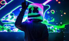 a person with a hat on in front of a colorful light display at a nightclub