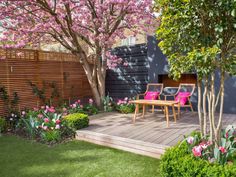 an outdoor deck with pink chairs and flowers in the foreground, surrounded by green grass