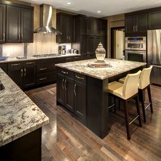 a kitchen with black cabinets and marble counter tops