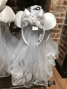 two white minnie mouse ears with tulle and bows on display in front of a brick wall