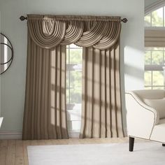 a living room with a couch, chair and window curtained in beige drapes