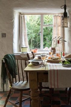 a dining room table is set with food and wine glasses on it, along with an open window