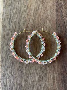 two pairs of beaded hoop earrings sitting on top of a wooden table