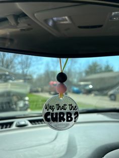 a car dashboard with a hanging ornament that says was that the curb?