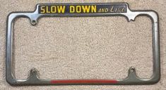 a license plate frame with the words slow down and live written in red on it