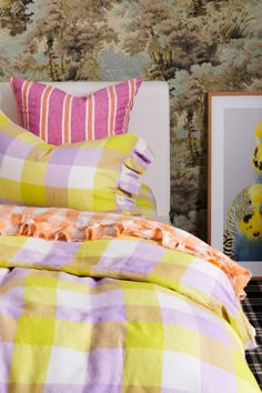 a bed with yellow and pink checkered comforter next to two pictures on the wall