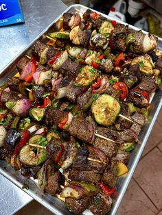 a tray filled with meat and veggies on skewers