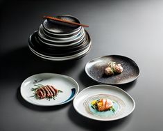 three plates with different types of food on them sitting next to a stack of stacked plates