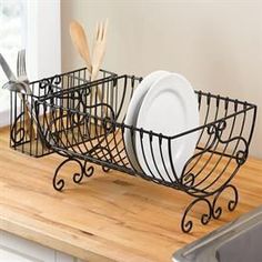 a black wire basket with plates and utensils in it on a wooden counter