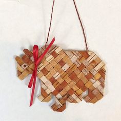 a wooden bear ornament hanging on a string with a red ribbon around it