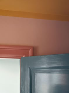 an open door in a room with pink and blue paint on the wall behind it