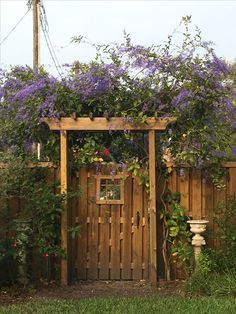 a wooden gate with purple flowers growing over it