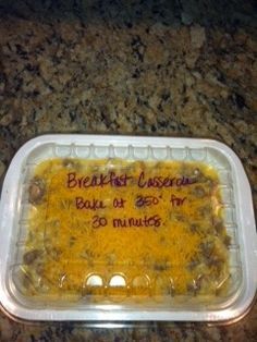 a plastic container filled with food sitting on top of a granite countertop next to a sign that says breakfast casserole