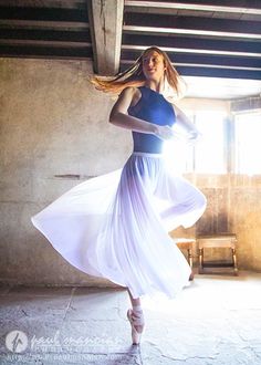 a woman in a blue top and white pleated skirt is posing for the camera