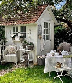 a small white shed sitting on top of a lush green field