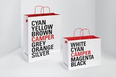 two white bags with red handles and black lettering on them, one is for camper orange silver