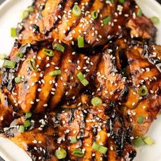 chicken with sesame seeds and green onions on a white plate