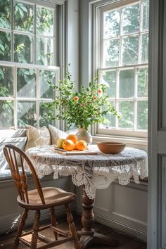 a small table with fruit on it in front of a window sill and some chairs