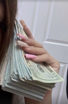 a woman holding stacks of money in front of her face