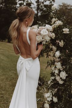 a woman in a white wedding dress holding flowers