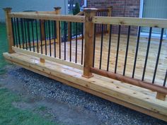 a wooden deck with metal railings in front of a house