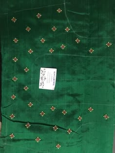 a piece of green cloth with small gold flowers on it and a white sticker in the middle