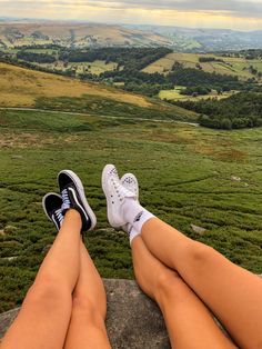 a person sitting on top of a rock with their legs crossed looking out over the countryside