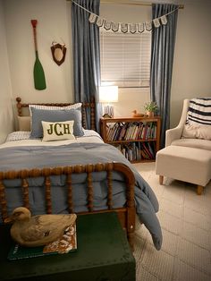 a bed room with a neatly made bed next to a chair and bookshelf