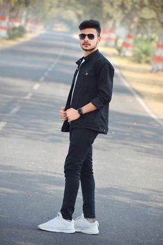 a man standing in the middle of an empty road wearing sunglasses and a black jacket