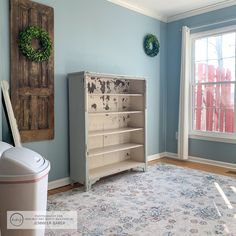 a room with blue walls and an old dresser in the corner next to a trash can