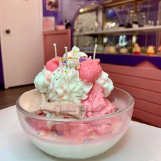 an ice cream sundae with sprinkles and candles in a glass bowl