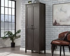 a brown armoire sitting next to a chair in front of a white brick wall