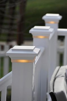 three white posts with lights on them near a fence