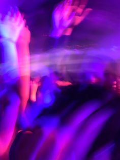 blurry photograph of people dancing in a club or nightclub with purple and blue lighting