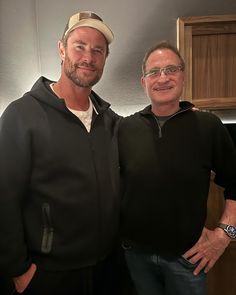 two men standing next to each other in a kitchen