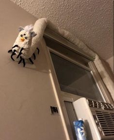 a stuffed animal hanging on the side of a wall next to an air conditioner