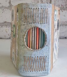 an old book with many colored pencils in the front and inside, sitting on a table