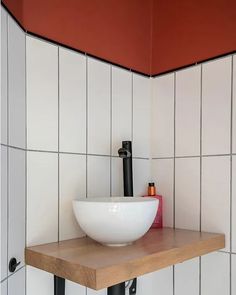 a white bowl sitting on top of a wooden shelf under a red ceiling light in a bathroom