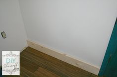 the corner of a room with a door and wood flooring on one side, and a blue door in the other