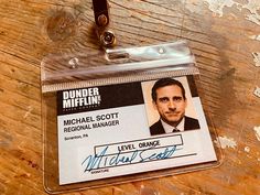 a id badge with a name tag attached to it on a wooden table, next to a pair of scissors