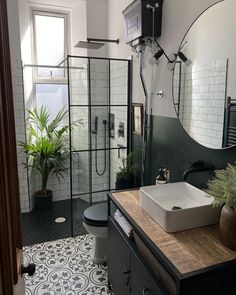 a black and white tiled bathroom with a sink, mirror, toilet and shower stall