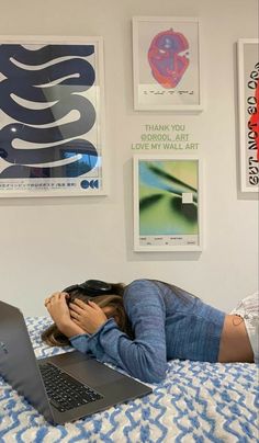 a woman laying on top of a bed next to a laptop computer