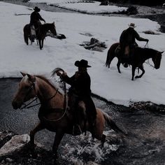 three men riding horses across a stream in the snow, with one man on horseback