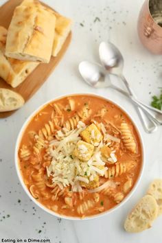 a bowl of pasta soup with bread and parmesan crackers on the side