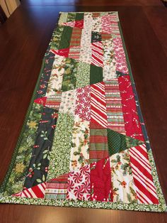 a table runner made out of many different types of christmas fabrics on a wooden floor