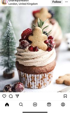 a cupcake with icing and berries on top is sitting next to some cookies